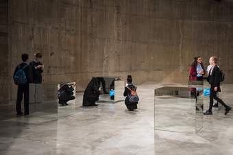Several students examine four large, mirrored cubes